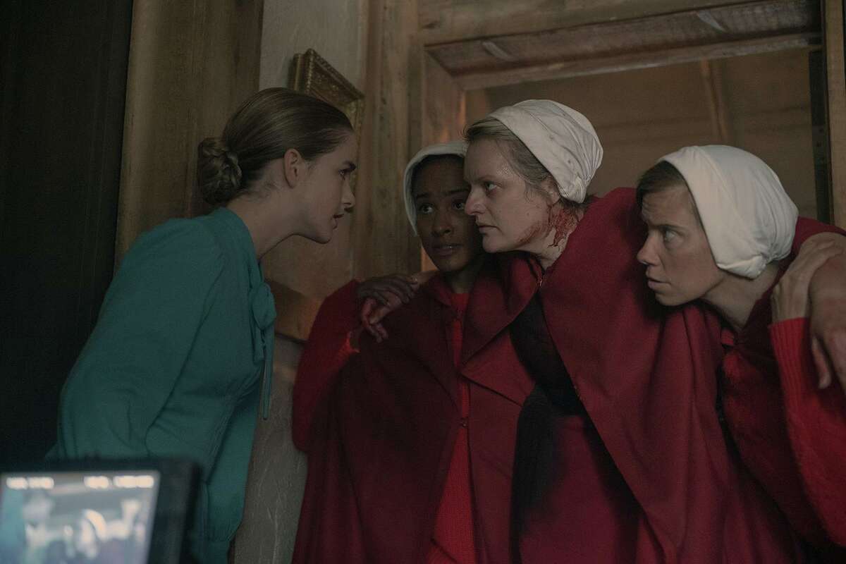 McKenna Grace, in blue, and Elisabeth Moss, center right, in season four of “The Handmaid’s Tale.” (Hulu/TNS)