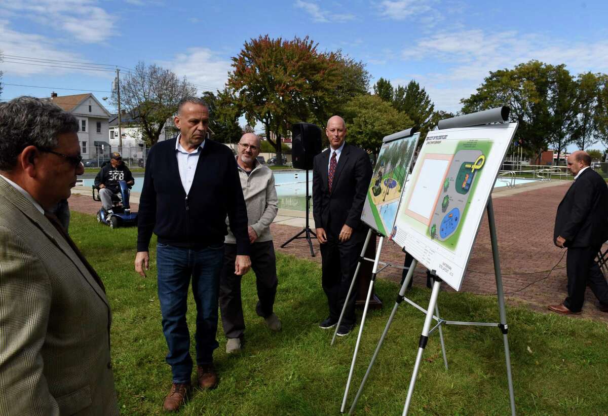 Watervliet Mayor Charles Patricelli, left, shows Scott Earl, Watervliet native and owner of Twin Bridges Waste Management and Prestige Vending, second from left, the drawings for redeveloping the Watervliet City pool made by Mark Aragona, Watervliet native and president of Wizard Works Design Group, third from left, on Tuesday, Oct. 19, 2021, in Watervliet, N.Y. A plan to develop a splash pad and playground for the pool with money donated by Scott Earl was announced during a press conference on Tuesday.