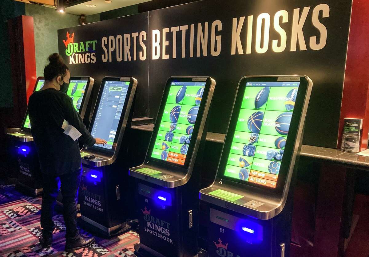 FILE - In this Thursday Sept. 30, 2021, file photo Zach Young, of New Haven, Conn., places a bet at one of the new sports wagering kiosks at Foxwoods Resort Casino in Mashantucket, Conn. Thousands of virtual bets started being placed early Tuesday, Oct. 19, 2021, the first day that online sports wagering and casino games were made available to all eligible adults within Connecticut.