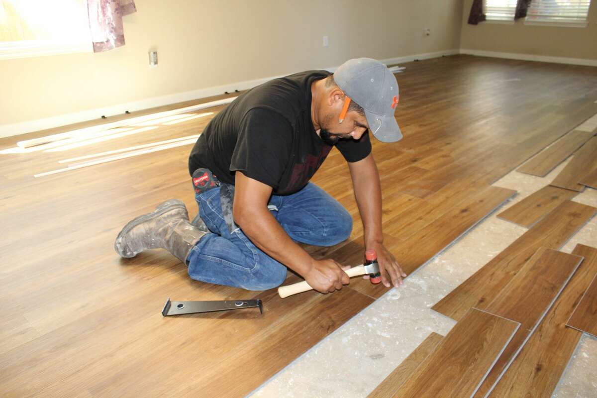 Carpenter installing luxury vinyl plank flooring.