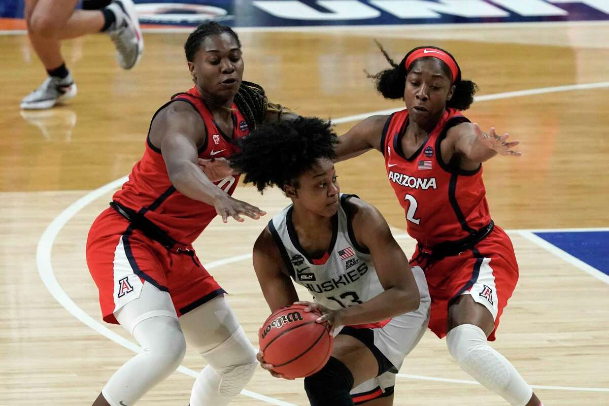 Connecticut guard Christyn Williams, center, looks to pass around Arizona forward Trinity Baptiste, left, and guard Aari McDonald (2) during the first half of a women’s Final Four NCAA college basketball tournament semifinal game on April 2 at the Alamodome in San Antonio.