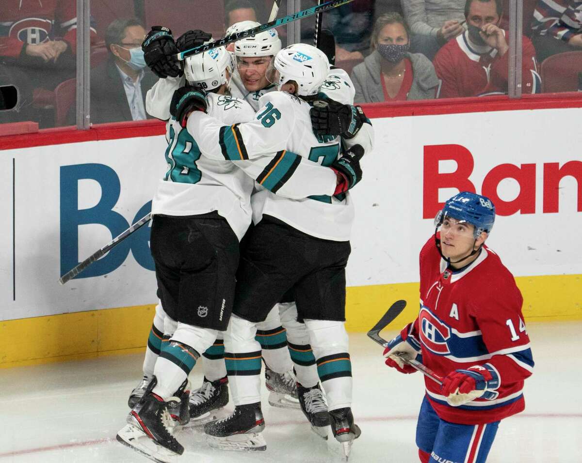 San Jose Sharks' Jonathan Dahlen (76) celebrates with Mario Ferraro (38) and Timo Meier (28) after scoring a goal, as Montreal Canadiens' Nick Suzuki (14) skates by during the first period of an NHL hockey game Tuesday, Oct. 19, 2021, in Montreal. (Ryan Remiorz/The Canadian Press via AP)