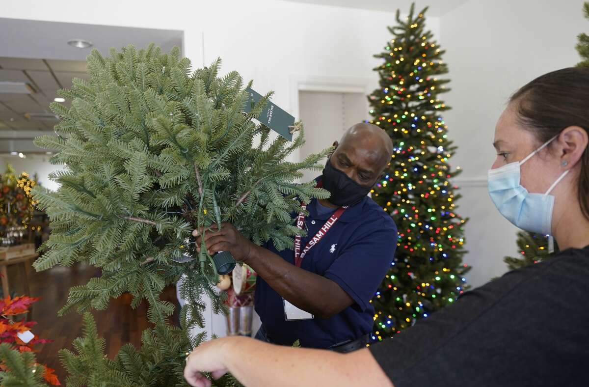 Balsam Hill Outlet retail manager Kelly Bratt (right)  helps sales associate Rickey Haynes as they set up a tree during on-the-job training.