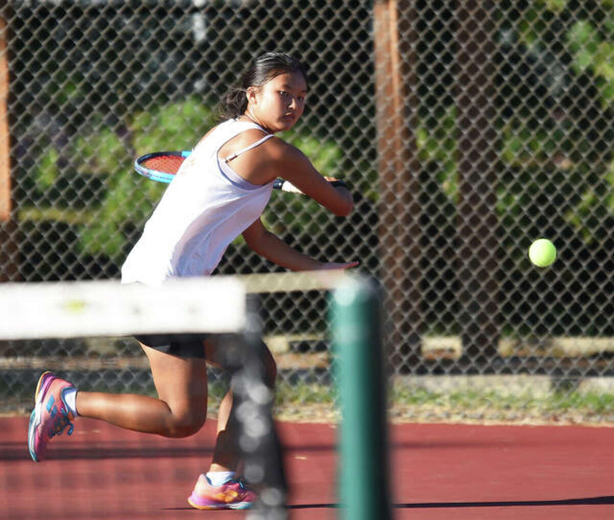 Edwardsville’s Chole Koons reaches for a shot during her singles match in the Edwardsville Sectional on Monday inside the EHS Tennis Center.