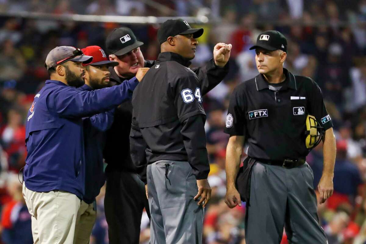 The official staff talks to Boston stadium staff about something in the outfield during the fifth inning in Game 5 of the American League Championship Series on Wednesday, Oct. 20, 2021, in Boston.