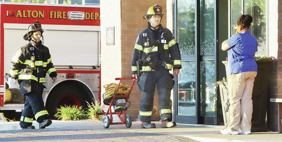 A woman, who was soon transported to a local hospital, coughs into her hands as firefighters bring exhaust fans into the Hampton Inn and Suites early Wednesday to investigate a report of smoke in a fourth floor room of the hotel. The smoke was determined to be aerosol mist from a bug bomb according to fire officials. Two women were transported to the hospital showing signs of smoke inhalation.