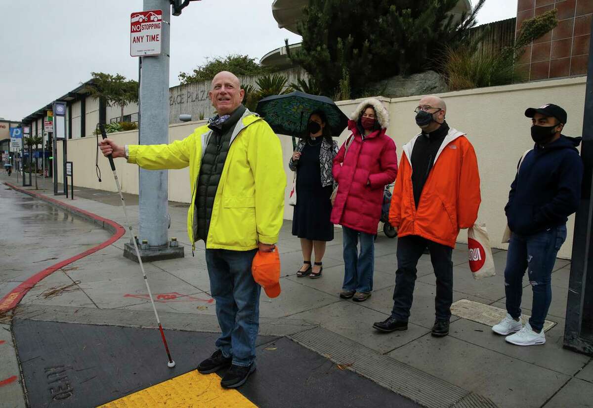 Lou Grosso (left) prepares to cross the street after a press conference celebrating the completion of the Geary Rapid Project.