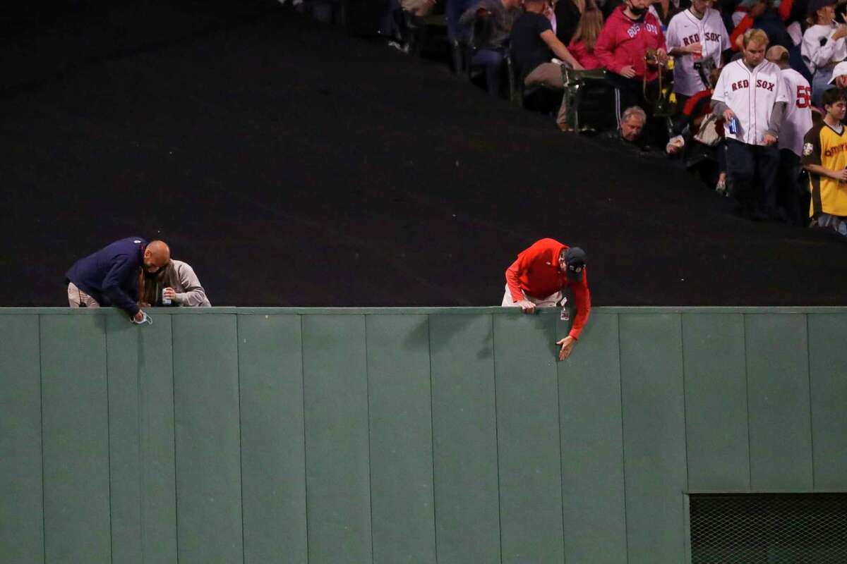 Facilities staff work on something on the center field wall that has attracted the attention of the umpires during the sixth inning in Game 5 of the American League Championship Series on Wednesday, Oct. 20, 2021, in Boston.