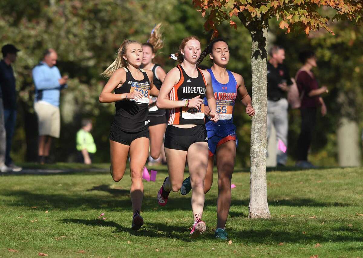 Ridgefield's Katie Rector (center), Danbury's Stephanie Queiroz (right) and Trumbull's Kali Holden (left) lead the way down a hill during the FCIAC girls cross country championship in New Canaan's Waveny Park on Wednesday, Oct. 20, 2021.