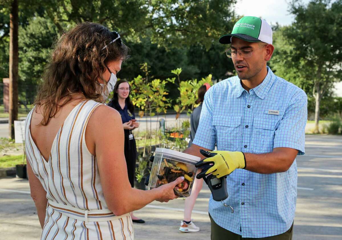 Sheila Ogden, left, hands off her compostable trash to Leonardo Brito – owner of Zero Waste Houston – at the Historic Heights Fire Station during the first day of the city's composting pilot program on Wednesday, Oct. 20, 2021, in Houston. The program is aimed at educating residents about the benefits of composting and preventing food waste from reaching landfills. During the six-week period residents will have once-a-week composting drop-off locations available at The Historic Heights Fire Station, Houston Botanic Garden, and Kashmere Multi-Service Center.