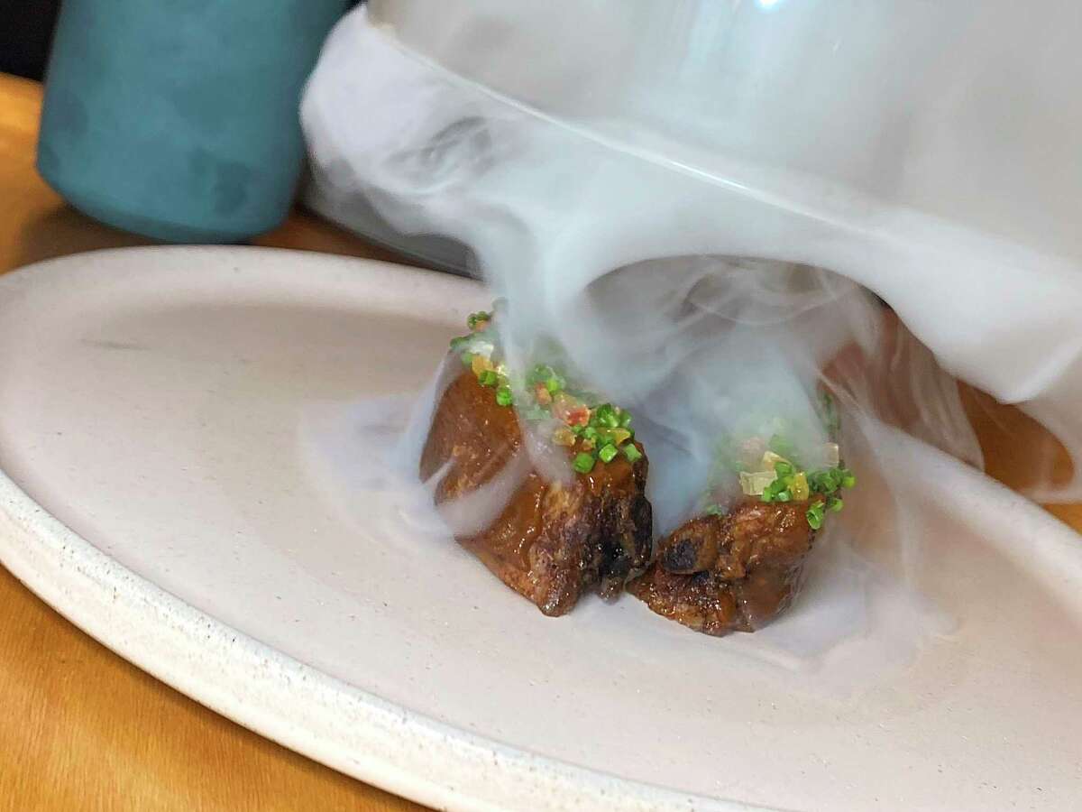 The Chiapas Mixtli menu features pork chops smothered in a Chiapas-style mole topped with candied mangoes, papaya and pineapple, served under a cherry smoke dome that is lifted to the table.