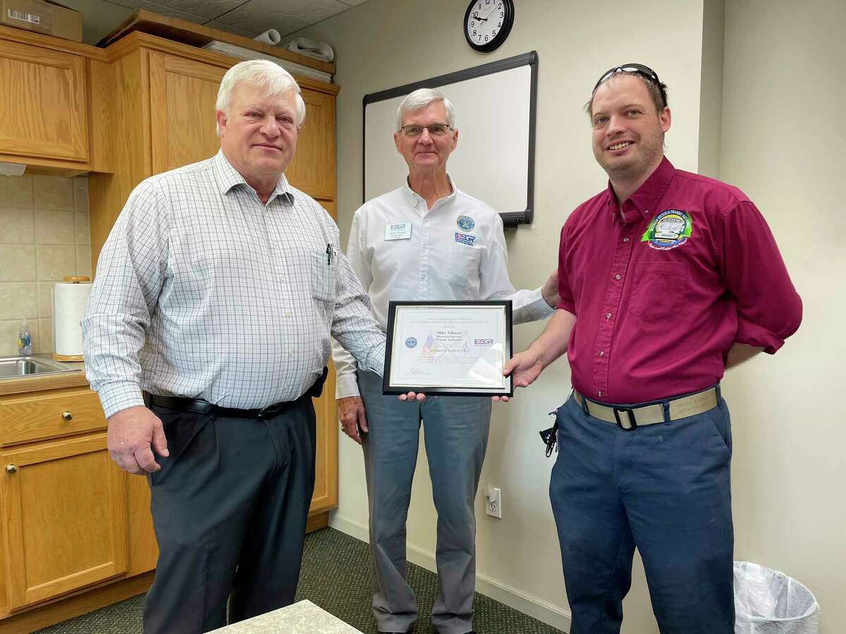 From left: Mike Tillman, executive director of the Mecosta Osceola Transit Authority, John Friedli, a military outreach coordinator with the Employer Support of the Guardian Reserve, and Doug Becker, a MOTA employee, share a smile with the camera shortly after a plaque presentation honoring Tillman. This week, Tillman was honored with a Patriotic Employer plaque from the Office of the Secretary of Defense Employer Support of the Guardian Reserve. (Pioneer photo/Bradley Massman)