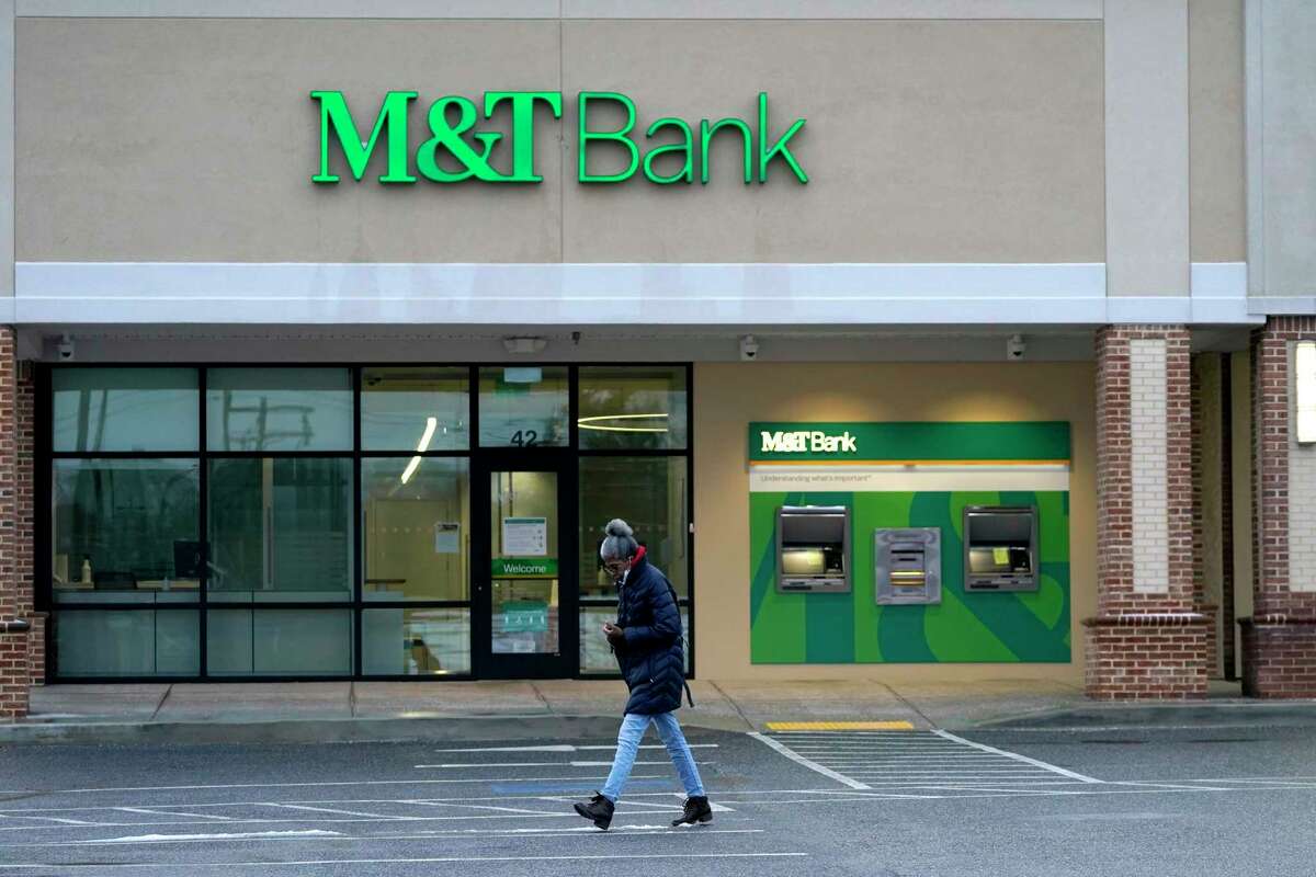 A person walks in front of an M&T Bank branch, Monday, Feb. 22, 2021, in Lutherville-Timonium, Md. M&T Bank Corp. is buying People’s United Financial Inc. in an all-stock deal valued at about $7.6 billion.