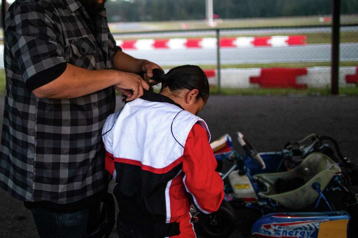 A.J., 9, a fourth grade student gets ready to go drive a go-kart while his father who also has long hair helps him get ready tucking in his child’s hair, Thursday, Oct. 21, 2021, in New Caney. A.J. has stopped attending his local public school due to Magnolia ISD's grooming policy, which mandates that boys keep their hair short.