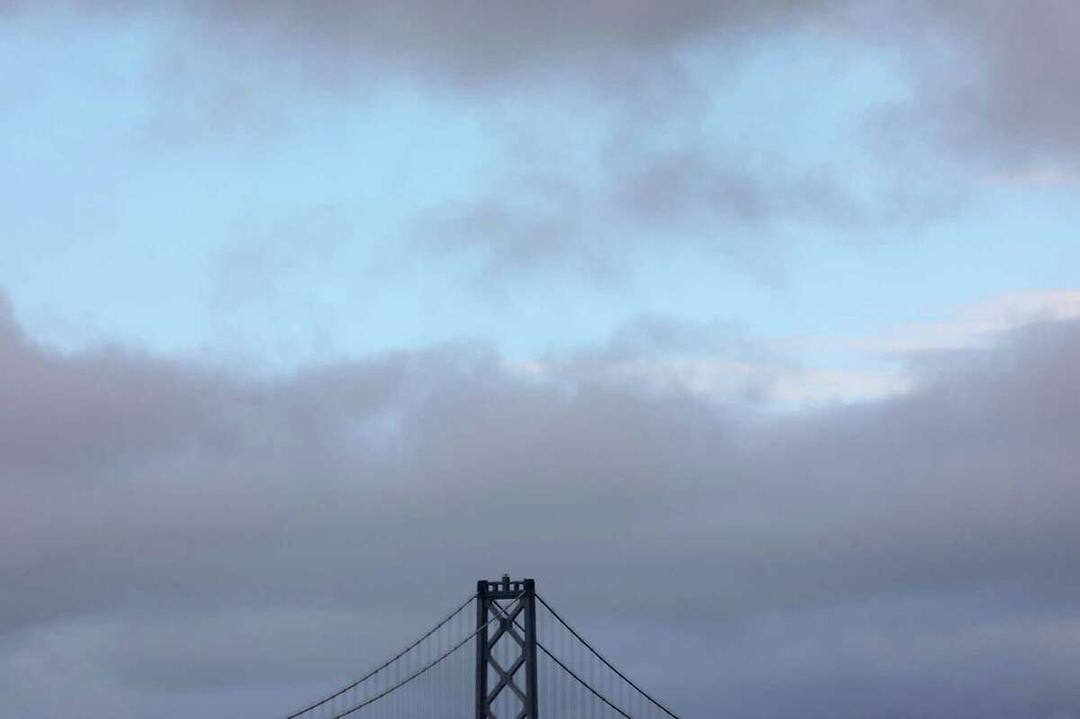 A spot of blue sky is seen through the clouds above the top of a tower of the Bay Bridge on 1 in San Francisco, Calif.