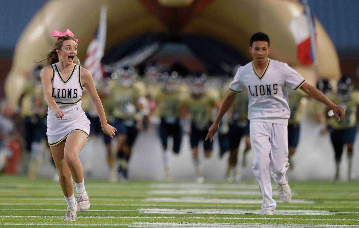Lake Creek cheerleader Sophie Smith, left, reacts beside Chris Kimble as she takes a running start for a tumble before a District 10-5A (Div. II) high school football game at MISD Stadium, Thursday, Oct. 21, 2021, in Montgomery.