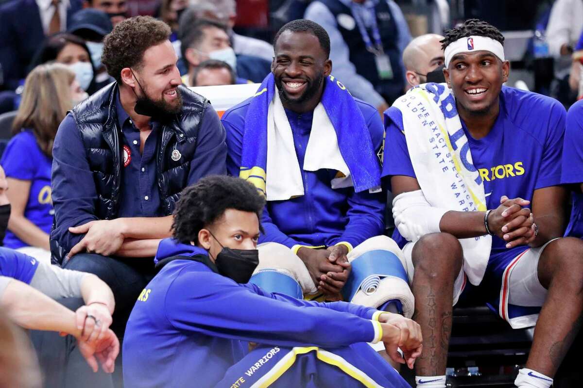 Golden State Warriors' Klay Thompson, Draymond Green and Kevon Looney laugh on the bench in 2nd quarter against Los Angeles Clippers during NBA game at Chase Center in San Francisco, Calif., on Thursday, October 21, 2021.