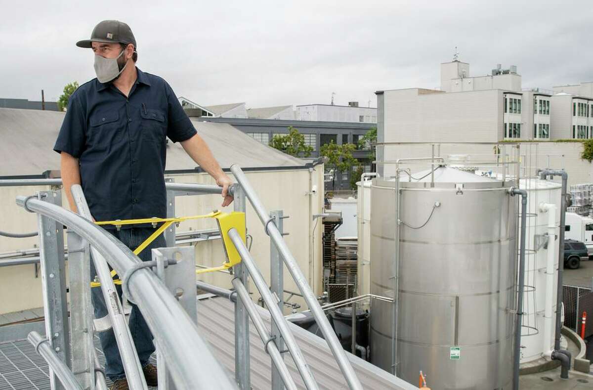 Travis Boland climbs to the top of a tank at Anchor Brewing Co., part of the city’s largest commercial water treatment facility.