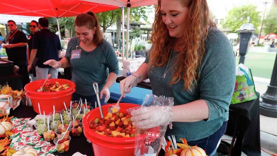 Danielle Steiner, right, and Roxann Johnson prepare fruit cups during the annual HEB Wine Walk, part of Wine and Food Week, at Market Street, Thursday, Oct. 21, 2021, in The Woodlands.