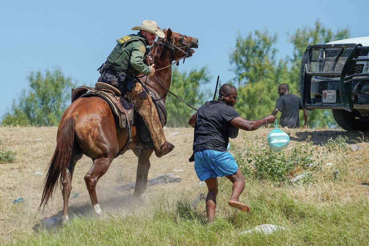 A U.S. Border Patrol agent on horseback uses the reins to try and stop a Haitian migrant from entering an encampment on the banks of the Rio Grande in Texas last month.