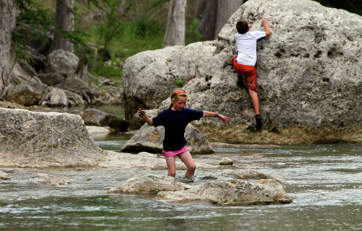 Brogan Ortman, 6 (left) of Spring Branch, Texas, weaves his way through the water in the Guadalupe River as his brother Liam Ortman, 11, climbs a boulder at Guadalupe River State Park on April 26, 2011.