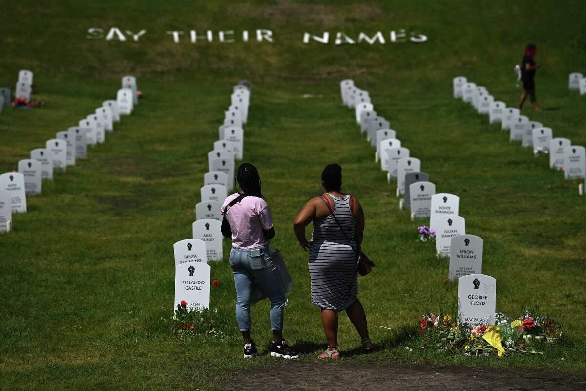 People stand at a makeshift cemetery during a remembrance gathering for George Floyd in Minneapolis on May 25, 2021.