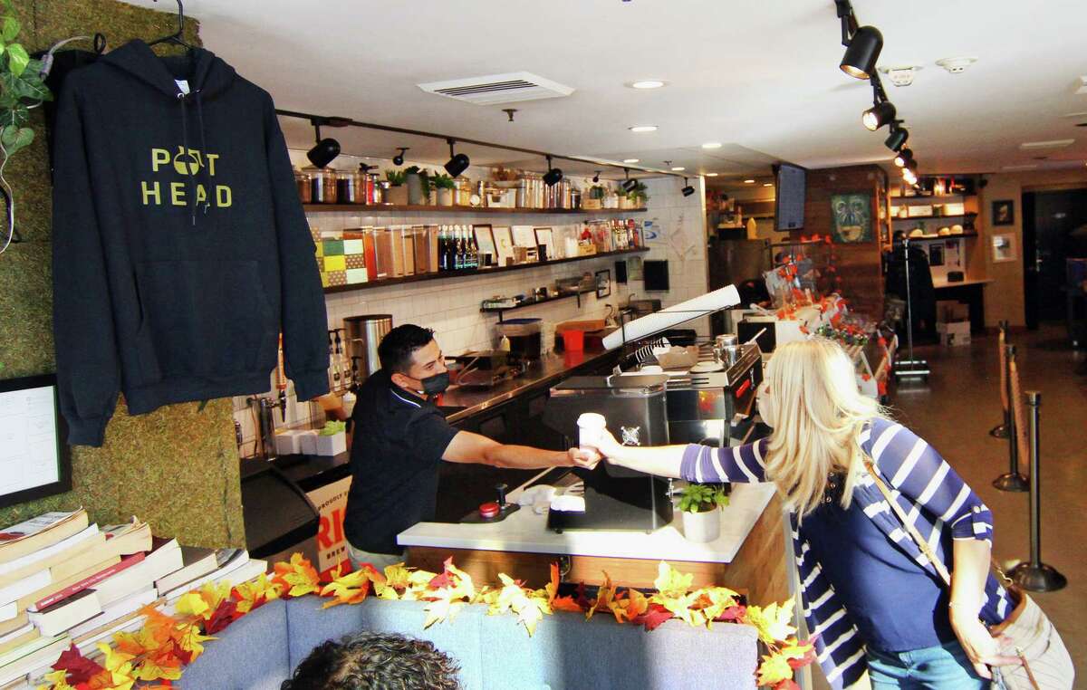 Winfield Street Coffee shop employee Gilber Escobar hands a beverage to customer Valeriane Costa at the business in downtown Stamford, Conn., on Friday October 22, 2021.