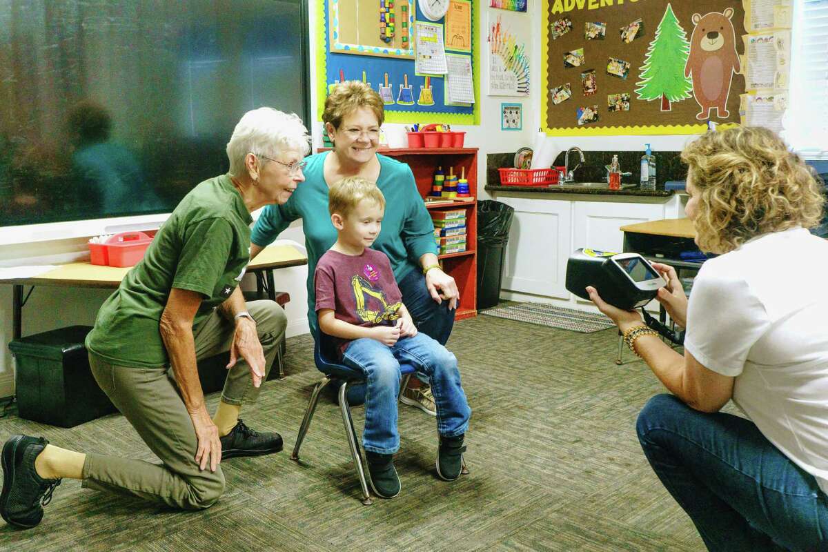 October is Vision Screening Month - In conjunction with the Conroe Service League the Conroe Noon Lions Club conducts vision screenings to area pre-schools. Here Lions Carmen Wainwright(l) and Connie Engle (c) assist a child while Lion Stacey Jata (r) uses the screening camera.