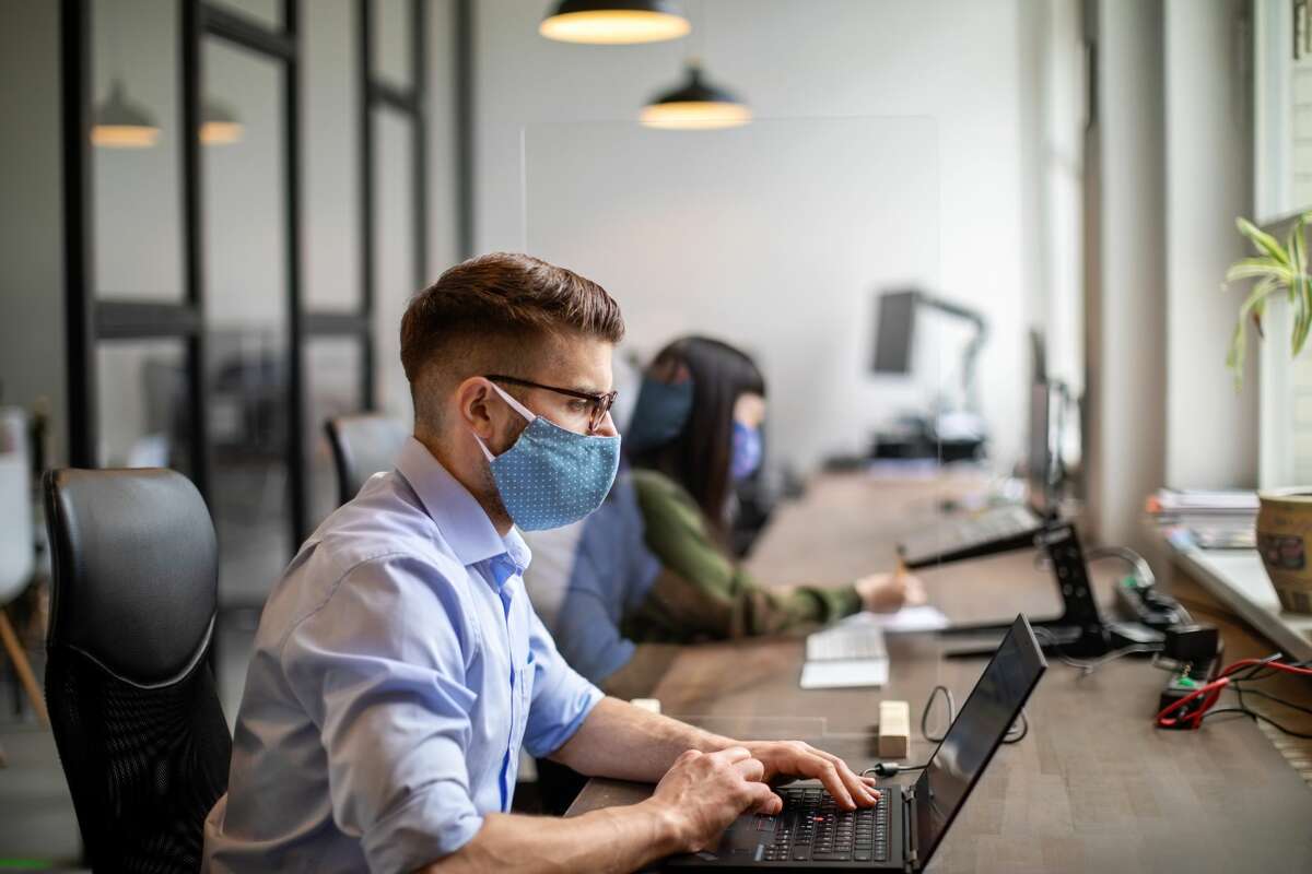 Businessman wearing protective face mask working at his desk. 