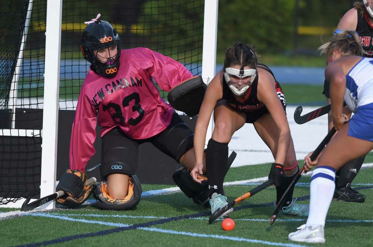 New Canaan goalie Grace Gilman and Keira Cooney (12) defend the cage against Darien during a field hockey game in Darien on Friday, Oct. 22, 2021.