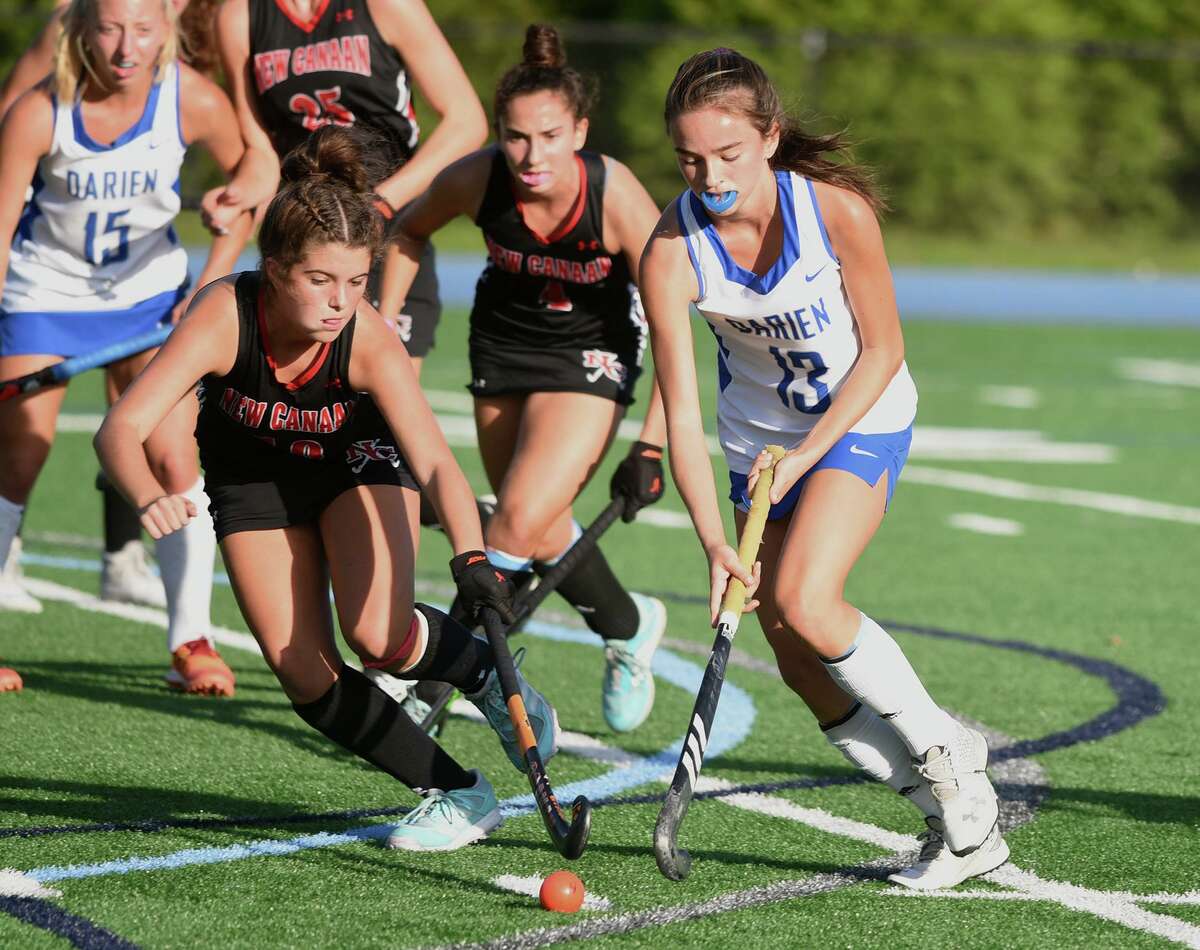 New Canaan's Sunny Jane Holland (10) and Darien's Ashley Stockdale (13) battles for the ball in the circle during a field hockey game in Darien on Friday, Oct. 22, 2021.