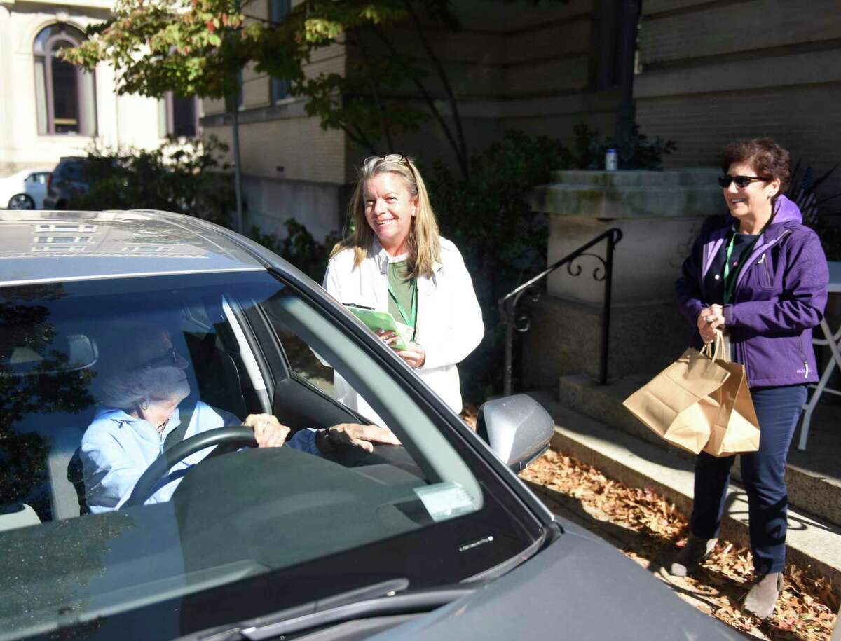 Deana Salerno, left, and Laurette Helmrich distribute bagged lunches outside the Senior Center in Greenwich, Conn. Tuesday, Oct. 19, 2021. The “Taste of the Town” partnership between the Greenwich Senior Center and local restaurants allows seniors to get a bagged lunch for just $5 from a rotating variety of local restaurants. About 150 bagged lunches are distributed in a drive-thru fashion once a week. Tuesday’s meal from Little Pub featured a generous helping of macaroni and cheese and a side salad.