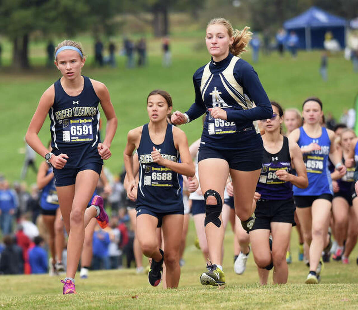 Father McGivney’s Elena Rybak, left, and Katelyn Hatley, center, make their way up the hill at the start of the Class 1A Belleville Althoff Regional.