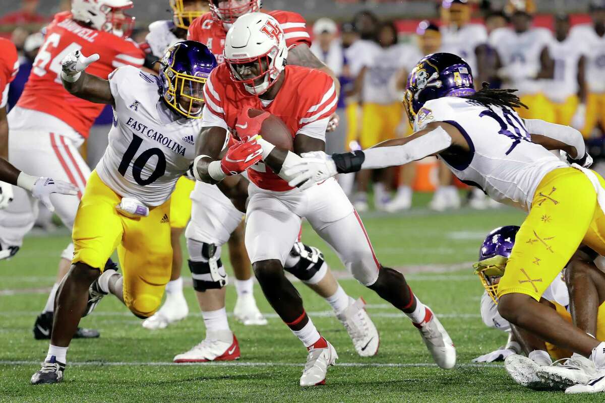Houston running back Alton McCaskill, middle, makes a gain between East Carolina linebacker Xavier Smith (10) and safety Gerard Stringer (30) during the first half of an ACC football game Saturday, Oct. 23, 2021 in Houston, TX.
