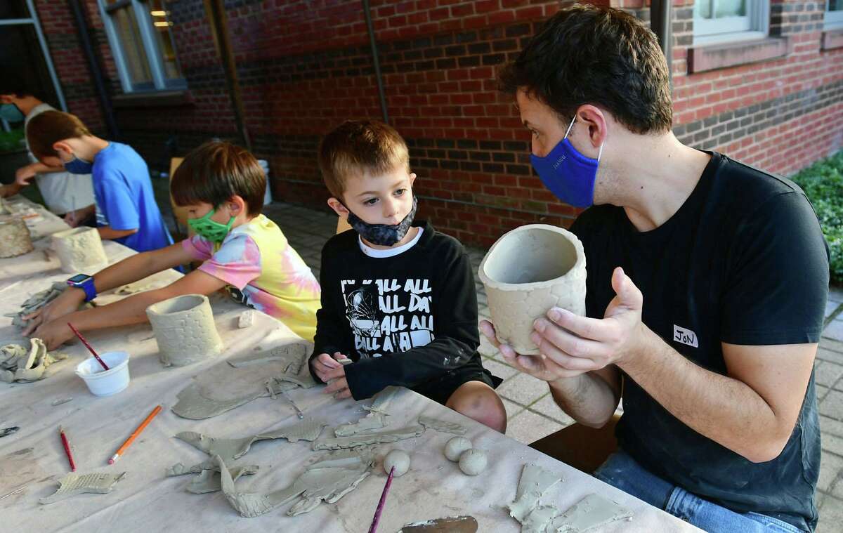 Young artists, including Porter Cooperman, 6, play with clay as they shape them into their own container while being instructed by professional potter, Jon Puzzuoli, on Friday at the Darien Library. The participants left their creations to be baked and will return to the library at a later date to pick them up.
