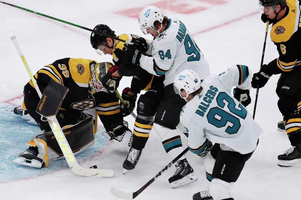 Boston Bruins' Linus Ullmark (35) smothers the puck as Brandon Carlo, center left, holds off San Jose Sharks' Alexander Barabanov (94) during the first period of an NHL hockey game, Sunday, Oct. 24, 2021, in Boston. (AP Photo/Michael Dwyer)