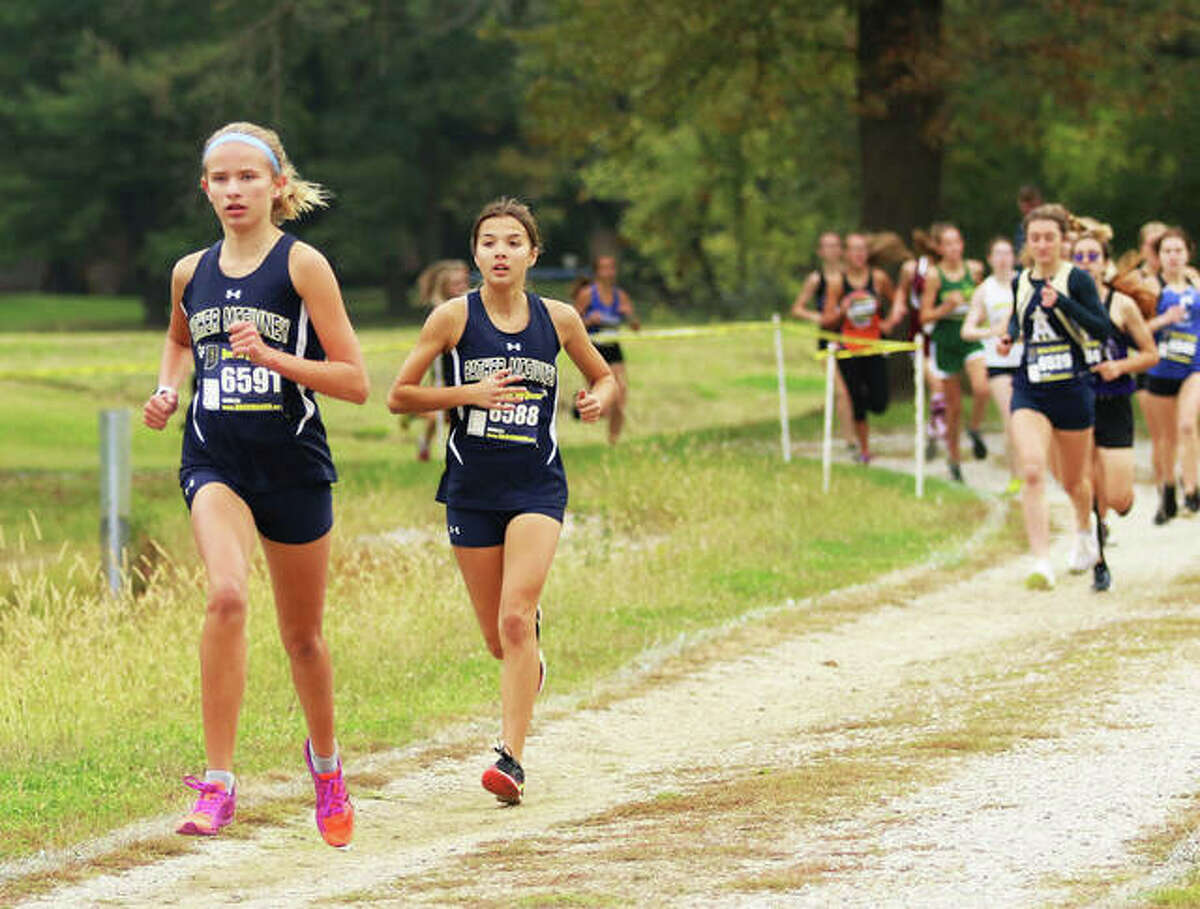 Father McGivney’s Elena Rybak (left) and Kaitlyn Hatley lead the field early in the race Saturday morning at the Belleville Althoff Class 1A Regional girls cross country meet at Clinton Hills Conservation Park in Swansea. Rybak won the race, with Hatley placing second.