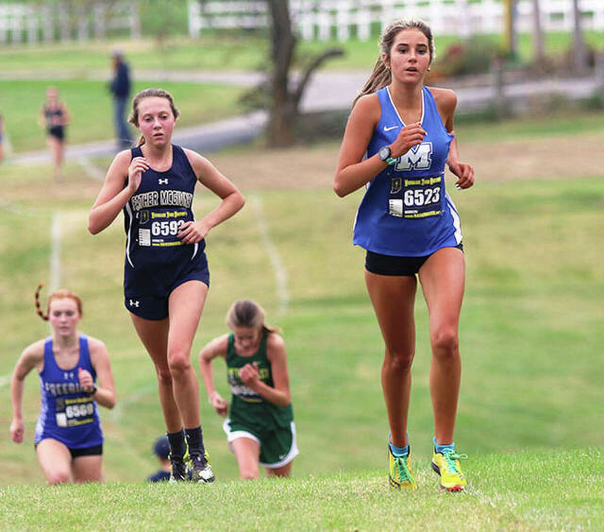 Marquette Catholic’s Kailey Vickrey (right) and Father McGivney’s Claire Stanhaus (left) run midway through the race Saturday at the Class 1A regional at Clinton Hills Conservation Park in Swansea.