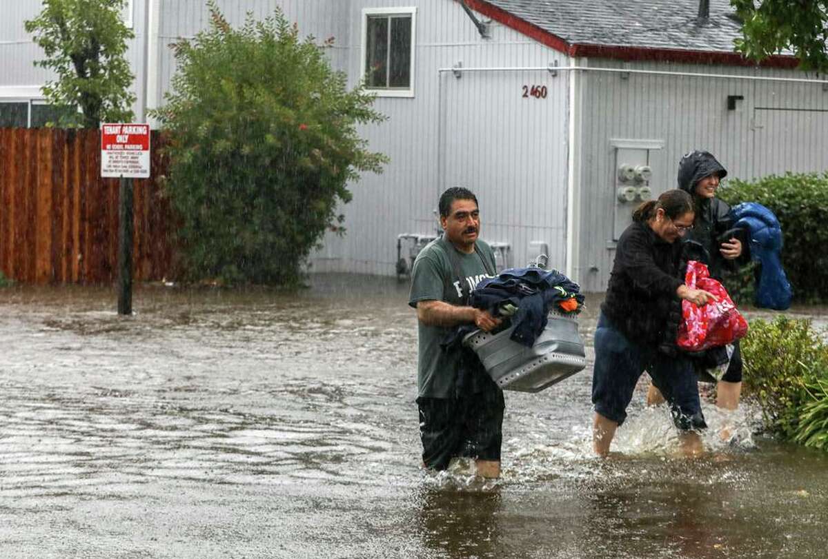Pablo Paredes and his wife Teresa walk with belongings as they evacuate their home at an apartment building in Santa Rosa, Calif. on Sunday, Oct. 24, 2021. Deemed by meteorologist as an “atmospheric river,” a series of rain storms continues to drench the Bay Area making it one of the biggest storms of the year.