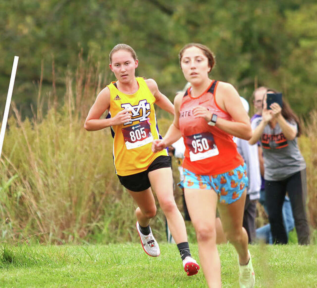 CM’s Hannah Meiser (left) runs behind Waterloo’s Angelynn Kanyuck at the MVC Meet on Oct. 14 at Principia College in Elsah. On Saturday in Alhambra, Kanyuck finished first with Meiser second in the Highland Class 2A Regional.
