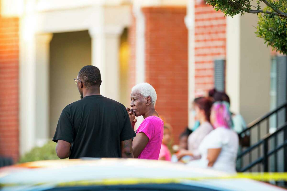 Neighbors watch from adjacent apartments as law enforcement officials investigate a scene where, according to Harris County Sheriff Ed Gonzalez, three juveniles were found living alone along with the skeletal remains of another person, possibly a juvenile, in a third floor apartment at the CityParc II at West Oaks Apartments on Sunday, Oct. 24, 2021, at in west Houston.