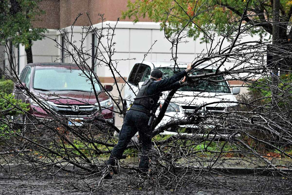 A Pleasant Hill Police officer attempts to pull a downed tree out of the way after it fell blocking Boyd Road in Pleasant Hill, Calif., on Sunday, Oct. 24, 2021. A powerful storm barreled toward Southern California after flooding highways, toppling trees and causing mud flows in areas burned bare by recent fires across the northern part of the state. (Jose Carlos Fajardo/Bay Area News Group via AP)