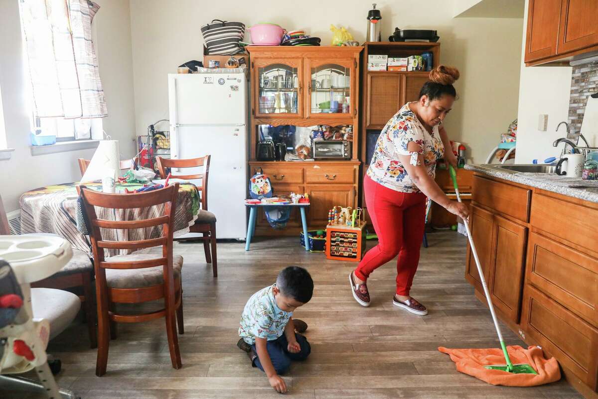 Mirna Arana mops after playing with her 3-year-old son, Aaron, in her Oakland home. Arana works as a house cleaner in S.F.