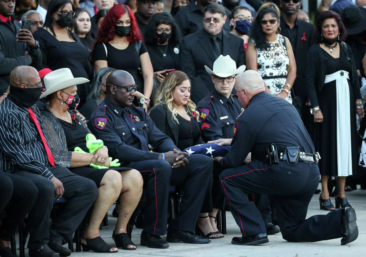 Nadia Aweineh, center, the wife of slain Harris County Pct. 4 Deputy Constable Kareem Atkins, receives a folded flag during his funeral Monday, Oct. 25, 2021, at Champion Forest Baptist Church in Houston. Atkins was killed in a shooting that also wounded two other deputy constables.