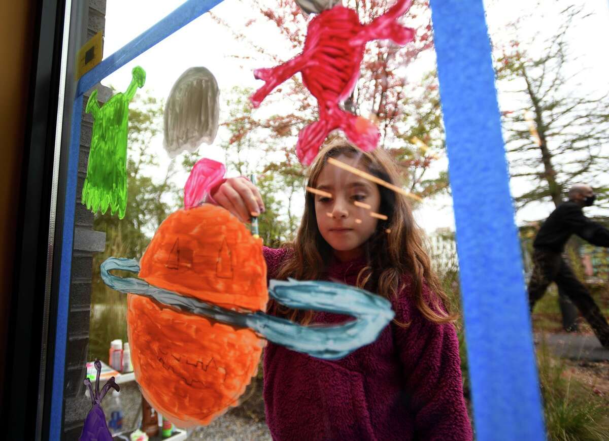 Clockwise, from top left; Chloe Robbin, 8, paints her original composition, the alien themed "Planet Pumpkin," on a window at the Westport Public Library. Scarlett Nathan, 7, paints on the window of a participating downtown business. Elise Mergenthaler, 12, paints on a window of Local to Market on Main Street. A haunted house is painted on a window as part of the Westport Chamber of Commerce's annual Halloween Window Painting Contest.