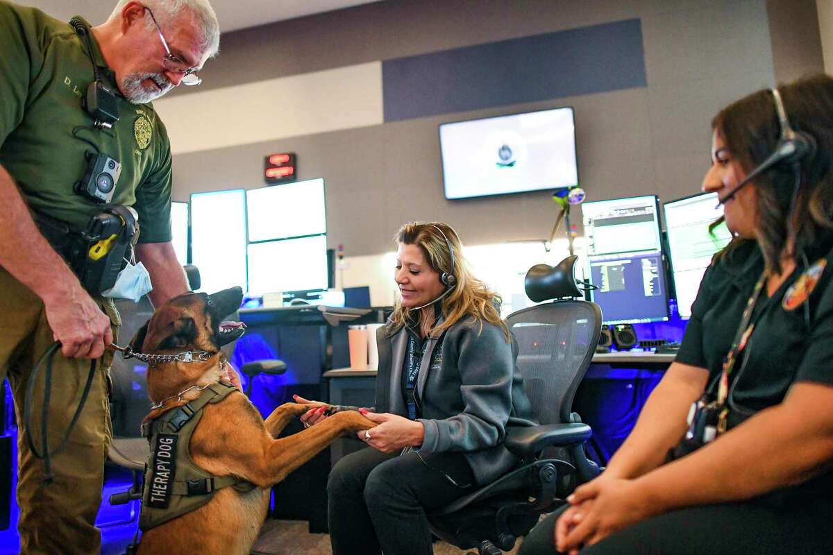 Rindr, a therapy dog with the San Marcos Police Department, and his handler, Donald Lee, visit with Hays County dispatchers Denise Lewis, middle, and Tori Tyler, right, on Monday, Oct. 25, 2021. The San Marcos Police Department's therapy dogs work out of the poice department's mental health unit. They respond to many incidents and also provide comfort to dispatchers, who sometimes call for them to relieve pressure of their high-stress jobs.