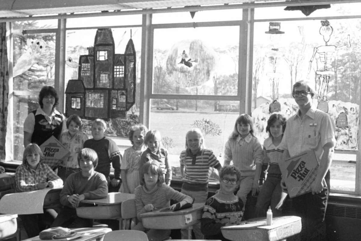 Mrs. Krolczyk's fifth grade class at North Elementary were treated to pizza from Pizza Hut for their first-place entry in the North Elementary window painting contest held last week. (Seated, in the front row) are Julie Zawacki, Mark Pehrson, Elaine Adamczak and Keith Bishop. (In the back row, front left to right) are Linda Andersen, from Pizza Hut, Shawn Bauman, Steve Schmeling, Robbin Clements, Tina Potter,  Alissa Hutson, Tammy Jans, Laurie Speck and Wayne Weberg, also from Pizza Hut. The photo was published in the News Advocate on Oct. 27, 1981. (Manistee County Historical Museum photo)