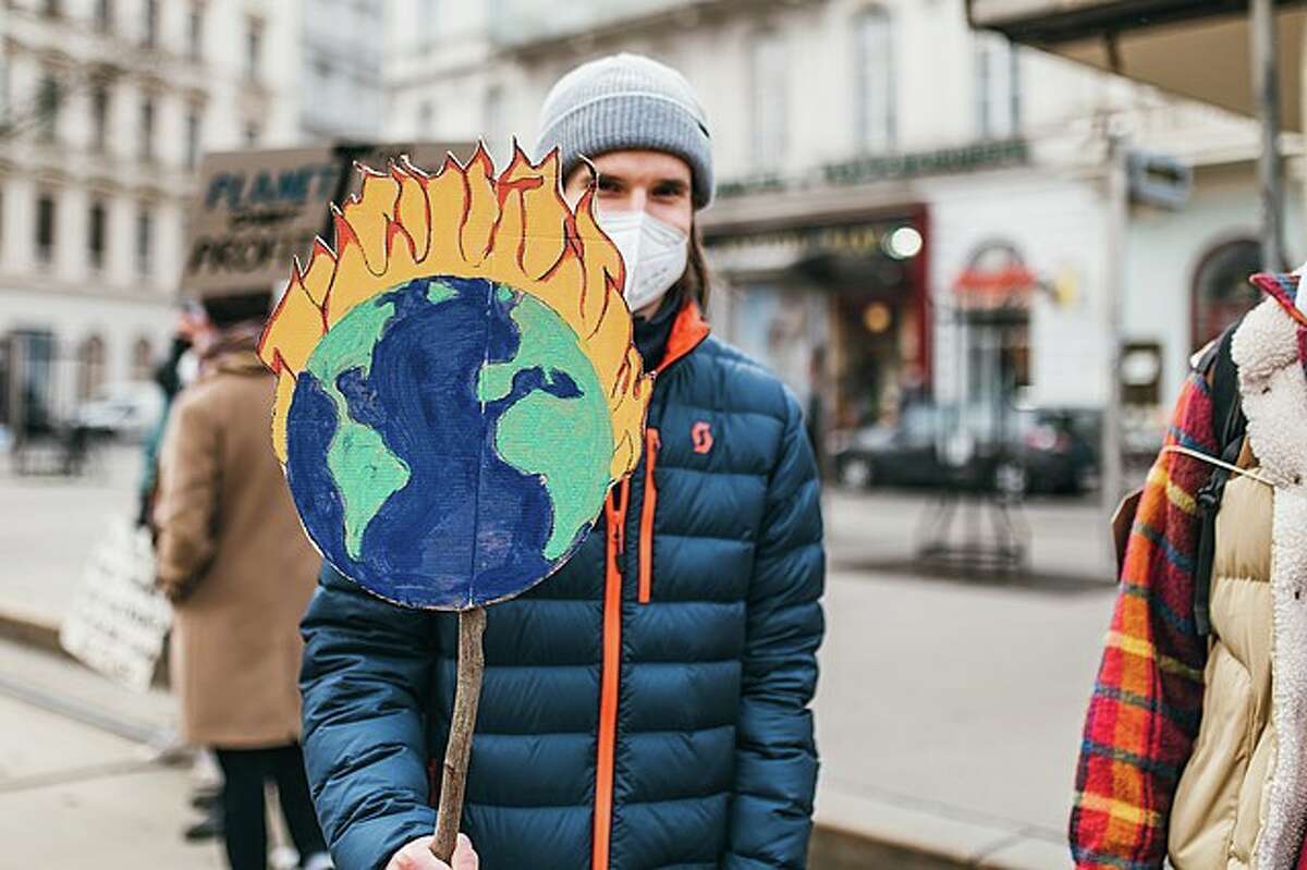 FILE — A protester holds a sign with a burning Earth at a protest against climate change.