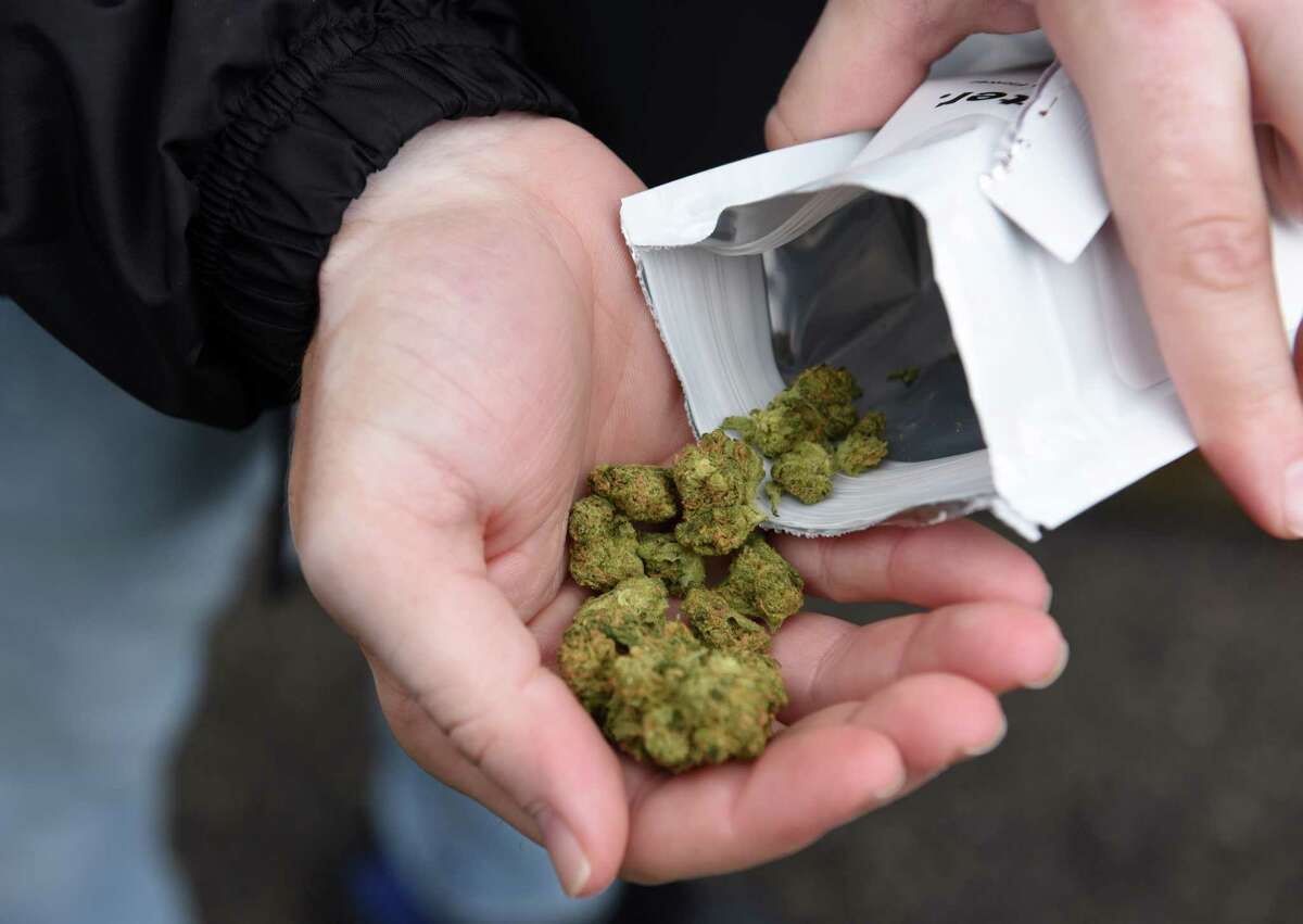 Jordan Bobrow, manager of sales at the Albany Verilife cannabis dispensary, holds a medical cannabis flowers that are now legal for purchase in New York on Tuesday, Oct. 26, 2021, at Tower Place in Guilderland, N.Y. Sales of whole cannabis flower had previously been prohibited. This was first sale of its kind made at the store.