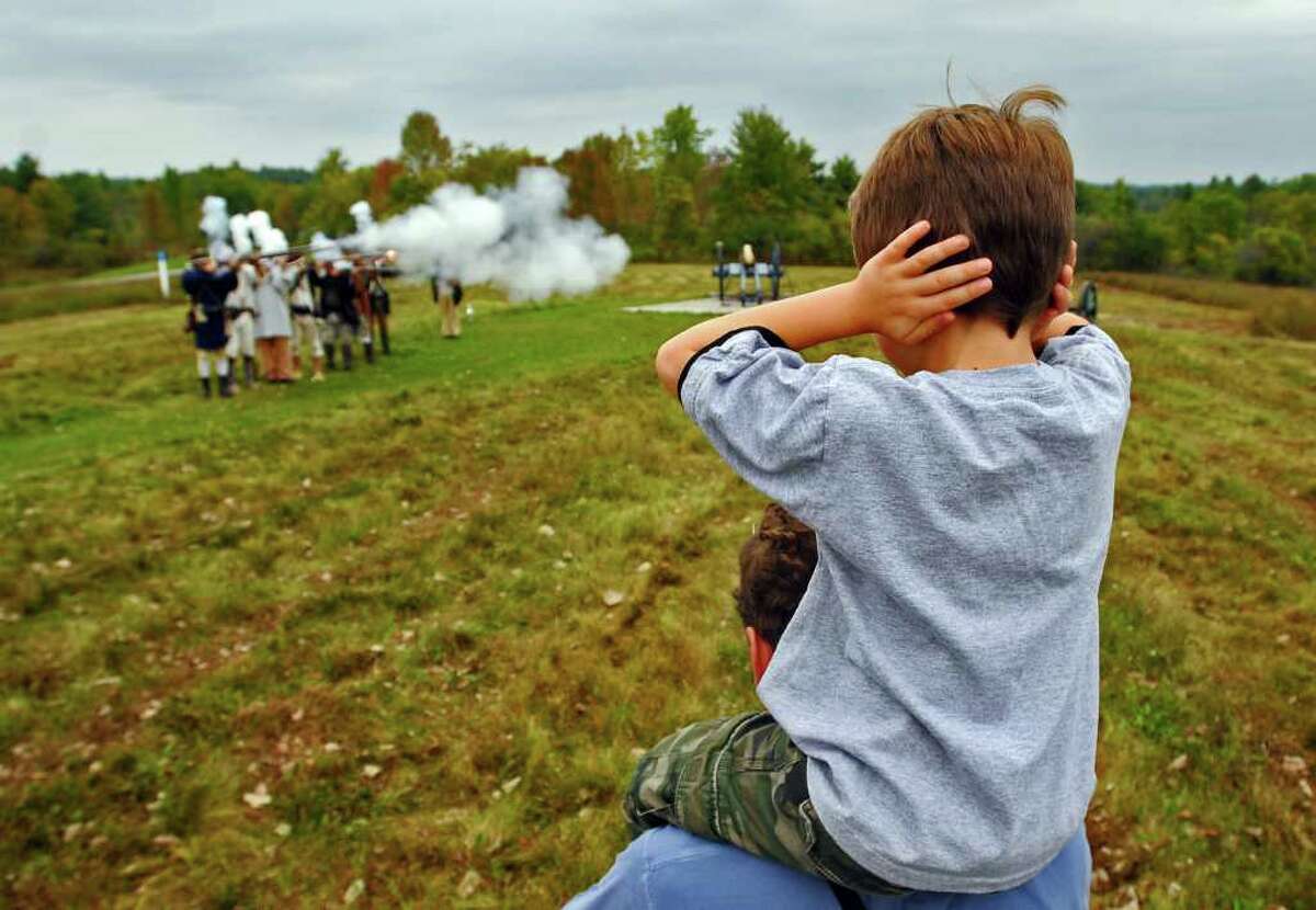 Will Marsh of Williamstown, Mass., 6, covers his ears while sitting atop his father Kevin's shoulders, as Continental Army reenactors fire their muskets, during Sunday's 233rd anniversary of the Battles of Saratoga, at the Saratoga National Historical Park in Stillwater. ( Philip Kamrass / Times Union )